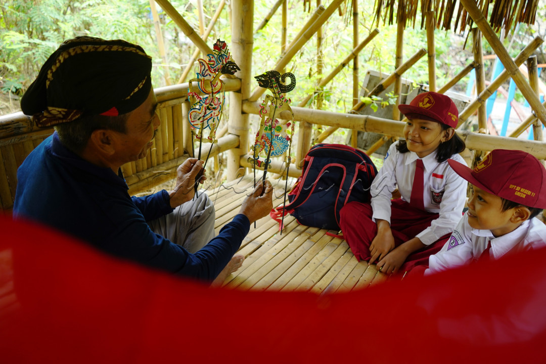 Potret Kakek sedang mengedukasi tentang saah satu budaya yang berada di indonesia terhadap dua anak siswa-siswi SD. edukasi tersbut dengan melalui karakter tokoh wayang kulit yang berada di Desa Sidorukun, Kabupaten Gresik, Jawa Timur, sabtu (08/07/2023). Sebagai media pembelajaran masyarakat luas, wayang juga sangat penting perannya bagi dunia pendidikan, mengingat pendidikan dan kebudayaan yang saling berkaitan erat. Dalam perannya sebagai media pembelajaran, wayang diharapkan mampu menyampaikan nilai-nilai kebudayaan kepada masyarakat terutama generasi muda.