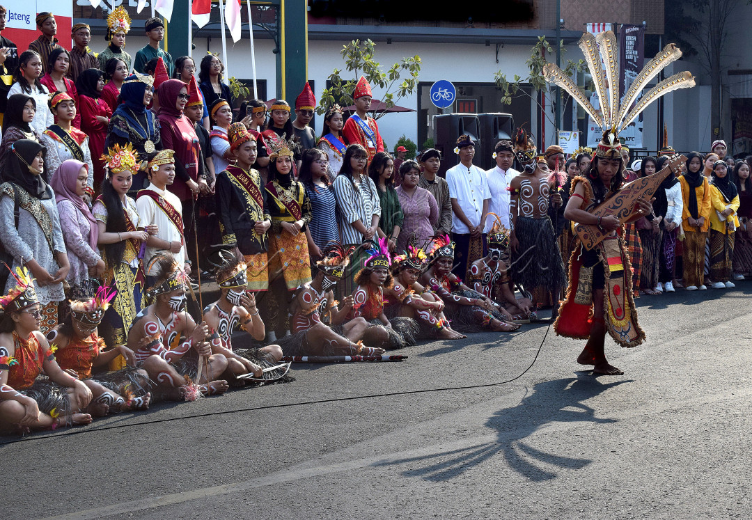 Seorang dengan pakaian adat Dayak bermain musik, dengan dikelilingi aneka ragam pakaian adat dari seluruh pelosok negeri.<br />
Membuktikan bahwa kita tetap dalam jiwa Bhinneka Tunggal Ika.