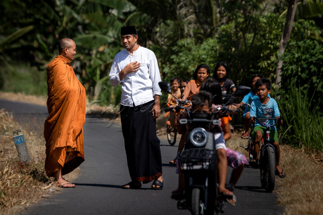 Dua orang berbeda agama asik mengobrol di sebuah jalan di desa Bentek, Lombok Utara. Pemandangan seperti ini sudah biasa bagi warga desa ini, bahkan sejak mereka kecil. Karena sejak zaman kerajaan, masyarakat sudah hidup berdampingan dengan menganut tiga agama berbeda yakni Muslim, Hindu, dan Budha, dan terpelihara hingga kini.