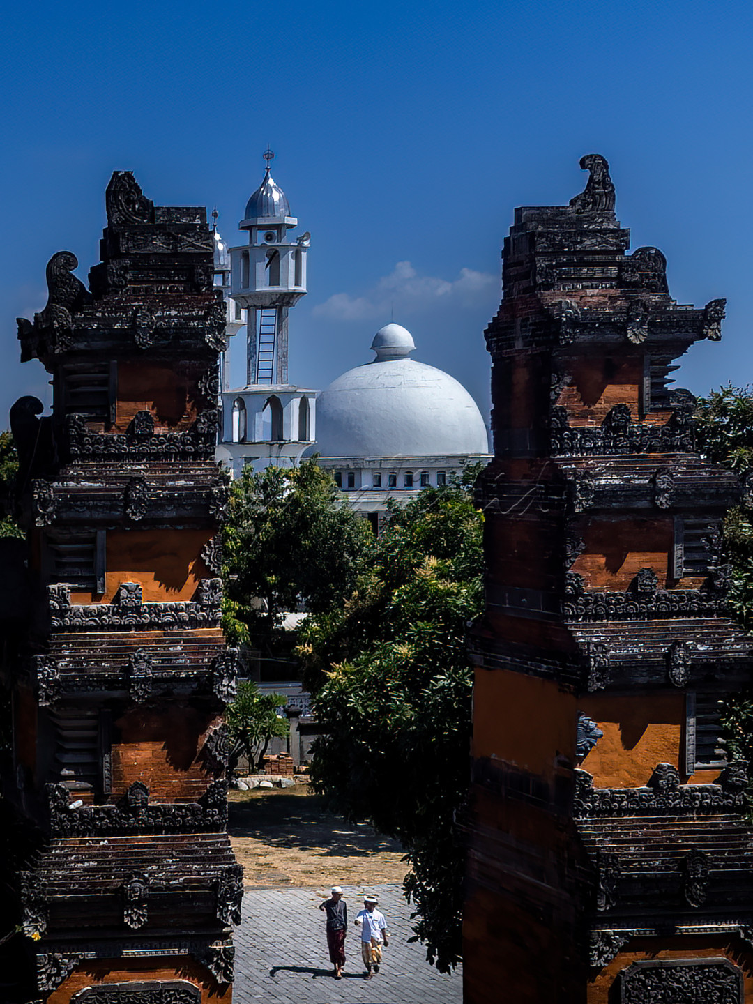 Dua orang pria berbeda agama berjalan diantara Pura dan Masjid di Kota Mataram. Dua bangunan simbol agama ini sudah dibangun zaman Raja Anak Agung untuk memelihara toleransi antar unat beragama di Pulau Lombok.&nbsp;
