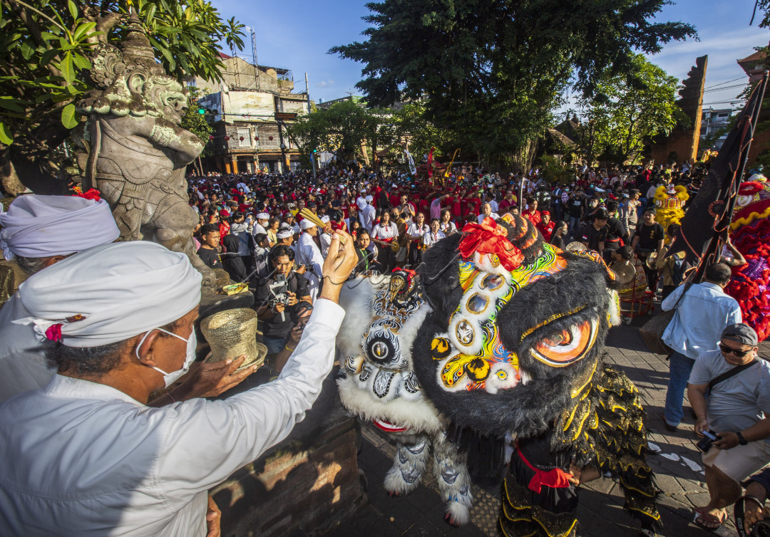 pemangku di bali sedang memerciki tirta ( air suci ) pertanda berkat unutk melaksanakan kegiatan pada hari raya imlek