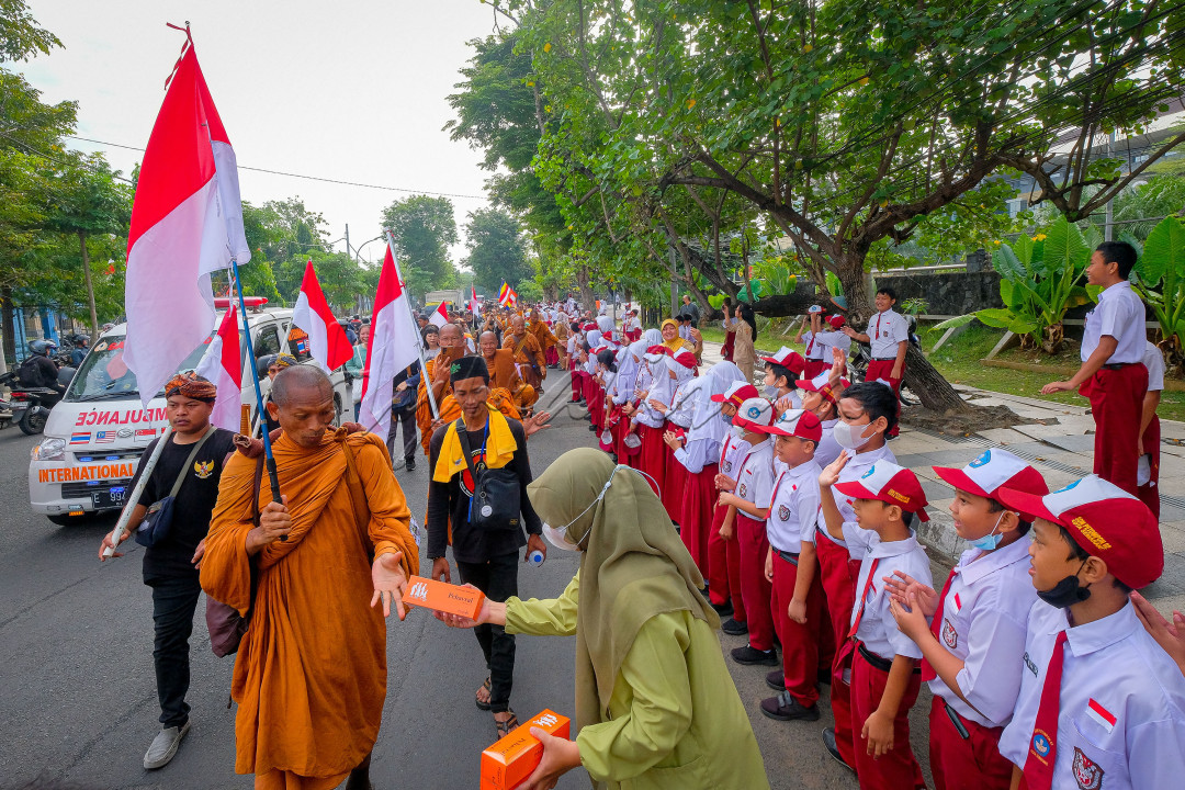 Seorang Muslimah berbagi kepada Biksu Tudong yang melintas di Jalan Kelud, Kota Semarang. Meskipun berbeda kepercayaan, tidak menghalangi persaudaraan dalam kemanusiaan.