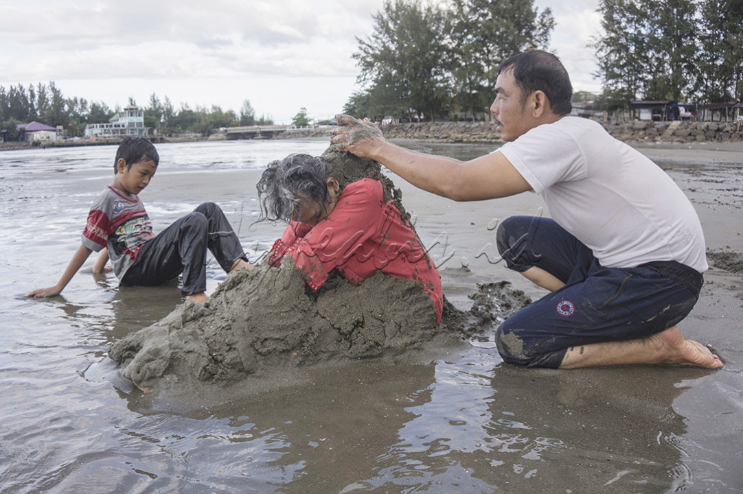 Seorang nenek penderita hipertensi menjalani terapi pasir laut dengan dibantu anak dan cucunya di pantai Ulhee Lheue, Banda Aceh, 16 November 2023.