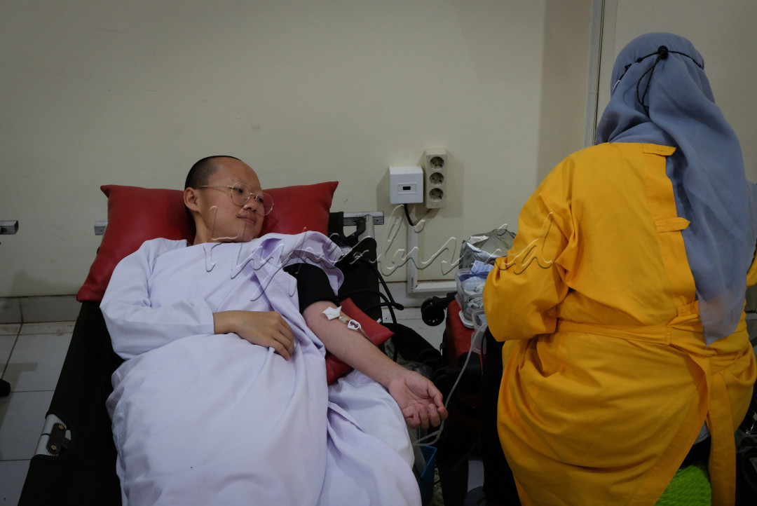 Seorang biksuni umat budha diambil darahnya untuk didonorkan darahnya kepada yang membutuhkan oleh petugas umat muslim.