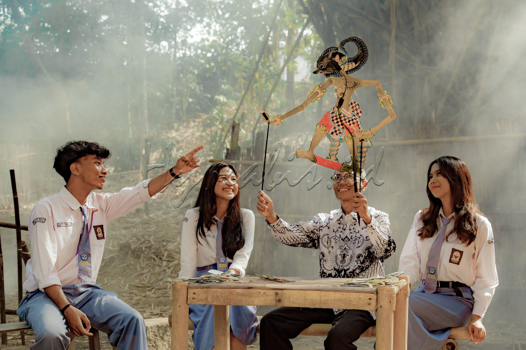 Gambaran seorang guru yang menunjukkan kepada para muridnya tentang Wayang kulit tradisional dan cerita tentang Wayang untuk pengenalan terhadap warisan budaya Indonesia untuk generasi muda penerus.