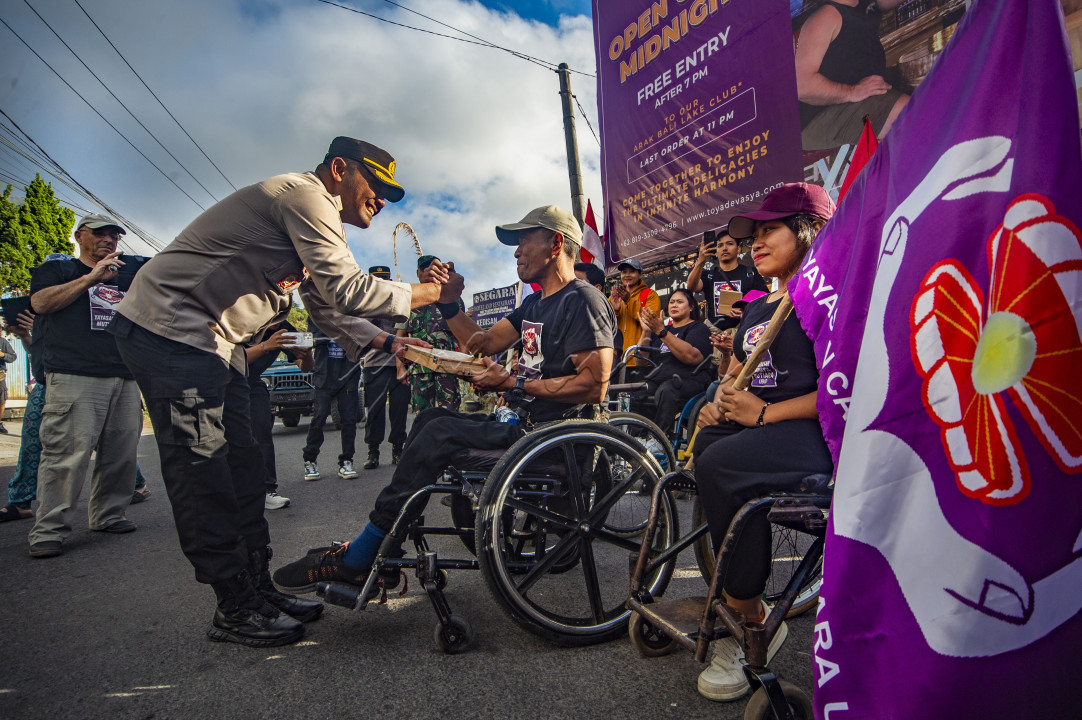 Seorang polisi yang memberikan semangat bagi para disabilitas dalam mengikuti rally dengan kursi roda dalam perayaan hari kemerdekaan RI di Kintamani Bangli