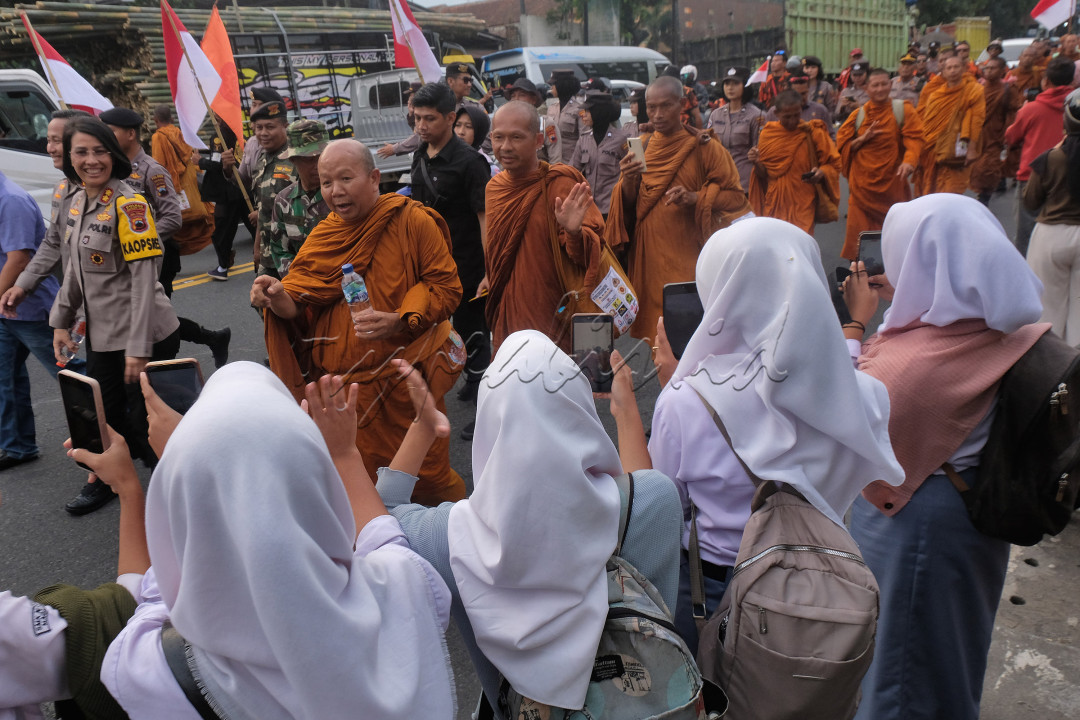 Sejumlah biksu peserta ritual Thudong menyapa warga yang menyambut di pinggir jalan raya kota Magelang, Jawa Tengah, Selasa (30/5/2023). Biksu Thudong mengaku sangat terharu dan tersanjung dengan sambutan masyarakat meskipun berbeda keyakinan.
