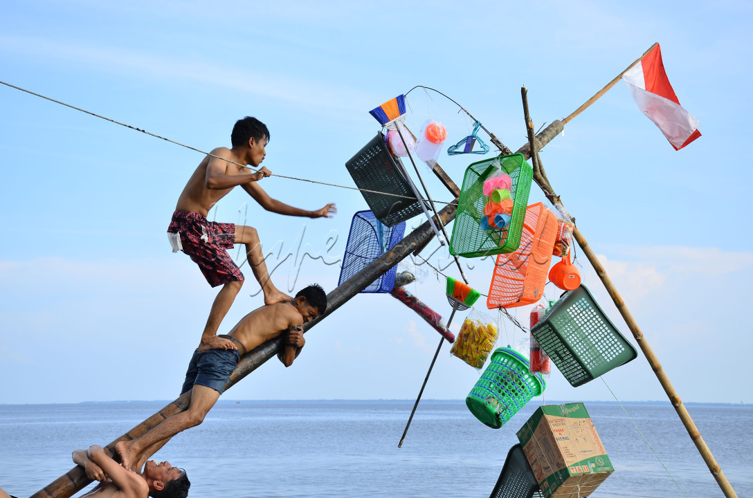 Lomba panjat pinang di tepi laut, Kabupaten Bengkalis, Provinsi Riau, Indonesia, Minggu (27/8/2023).