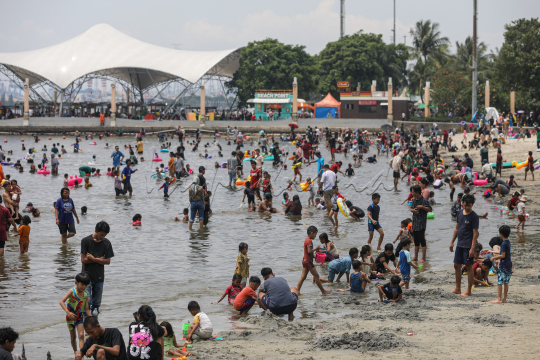 Puluhan ribu orang menyerbu kawasan wisata Ancol pada hari ke-2 Lebaran, memenuhi sejumlah titik pantai yang membentang. Panas terik matahari tak mengurungkan niat wisatawan untuk menikmati pasir dan hangatnya air laut.