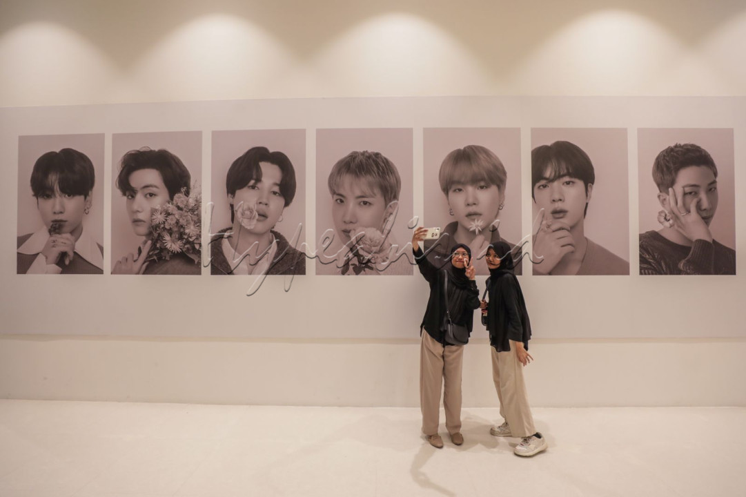 Penggemar BTS atau Army berswafoto di depan anggota poster BTS pada BTS POP-UP: MONOCHROME di Jakarta,