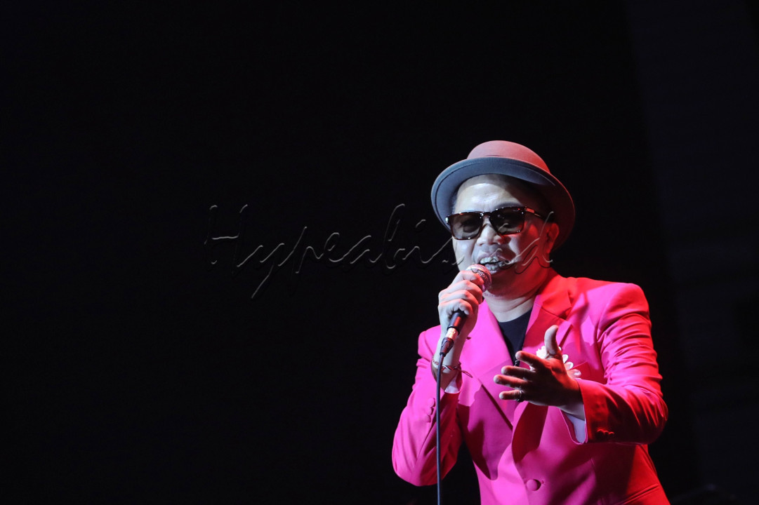 Sandhy langsung menggebrak panggung dengan lagu Dan Itu Yang Aku Cinta. Kharisma musisi paruh baya itu semakin terasa saat bernyanyi sambil menggerak-gerakkan kacamata hitamnya dalam aksi yang komikal. Kepalanya dihiasi topi fedora dan di saku bajunya tersangkut setangkai kembang Krisan.