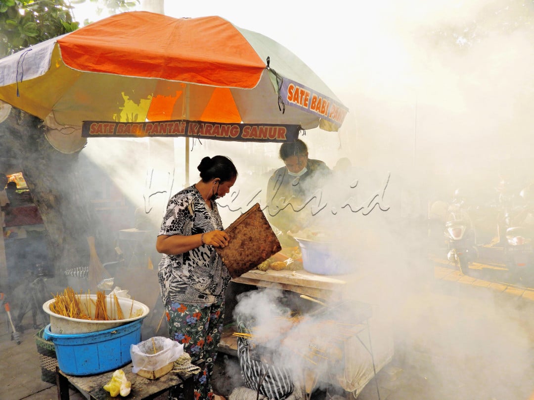 Ibu penjual sate tradisional Bali yang rutin mangkal pagi hari di Pantai Karang, Sanur, Bali.