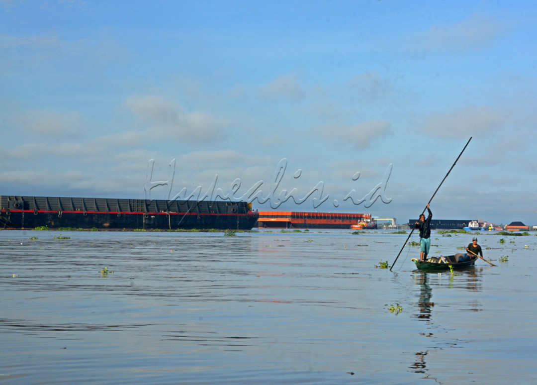 Aktivitas masyarakat di pinggir sungai Musi yang menggunakan perahu kecil berdampingan dengan hilir mudiknya tongkang batubara raksasa.&nbsp;