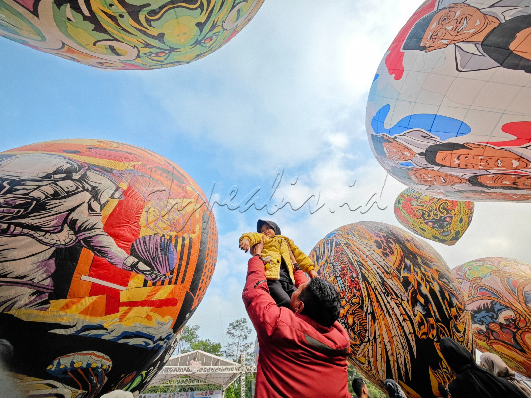 Seorang ayah menggendong anak untuk melihat balon raksasa pada event festival balon kalianget wonosobo 2024