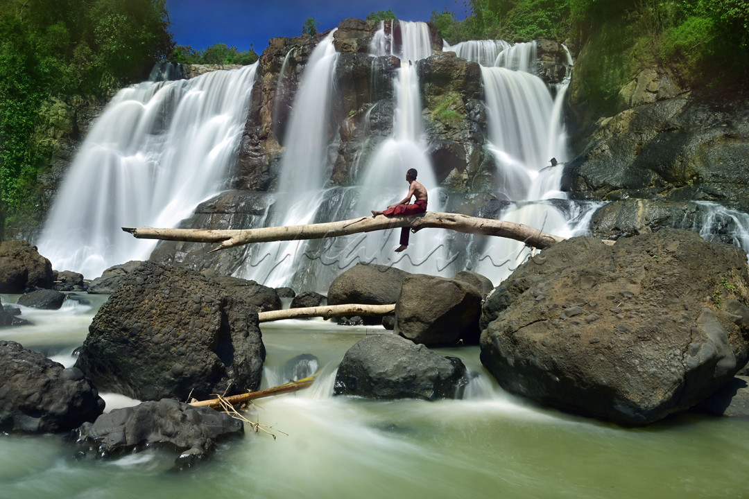 Keindahan pesona aliran sungai air terjun Curug Malela Kabupaten Bandung Barat, Jawa barat. Seseorang menikmati indah sunyi di sertai debur aliran air terjun diatas pohon tumbang yang terbawa aliran sunggai disaat air sungai meninggi karena intensitas air hujan yang tinggi.&nbsp;
