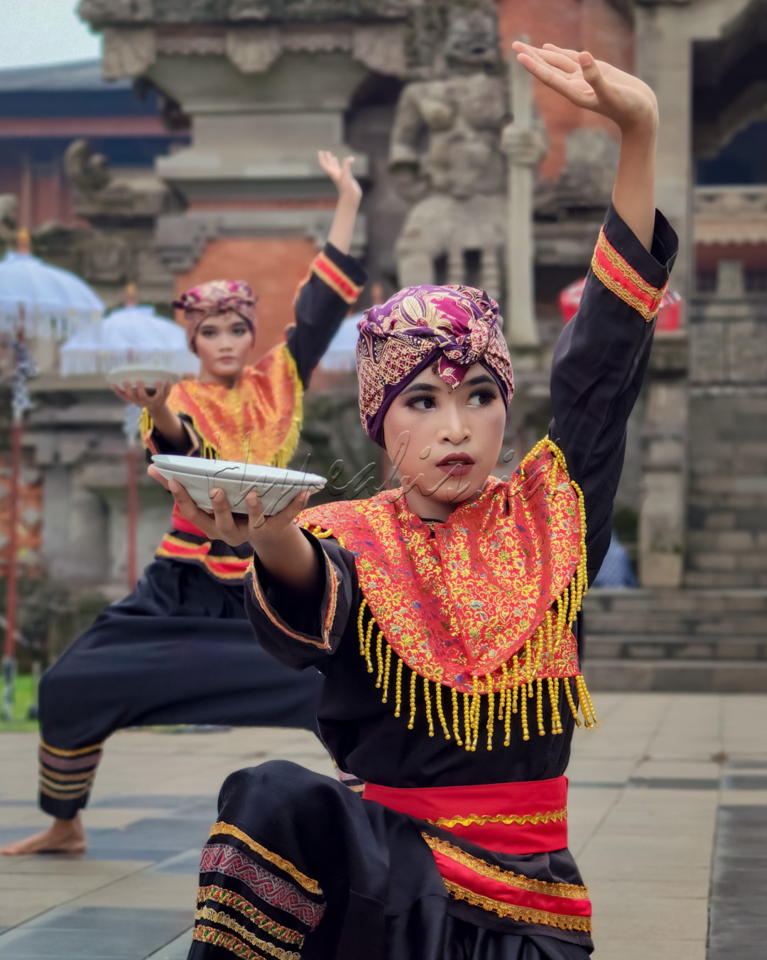 Dalam foto ini, terlihat dua penari tradisional Indonesia yang sedang mempersembahkan sebuah tarian khas Nusantara. Mengenakan busana adat yang kaya akan motif dan warna, gerakan tangan mereka yang anggun melambangkan keindahan dan keluwesan budaya Indonesia. Latar belakang candi tradisional menambah kesakralan suasana, mengingatkan kita pada kedalaman sejarah dan warisan budaya yang masih hidup hingga kini. Tarian ini bukan sekadar hiburan, tetapi juga merupakan simbol identitas dan kebanggaan bangsa.