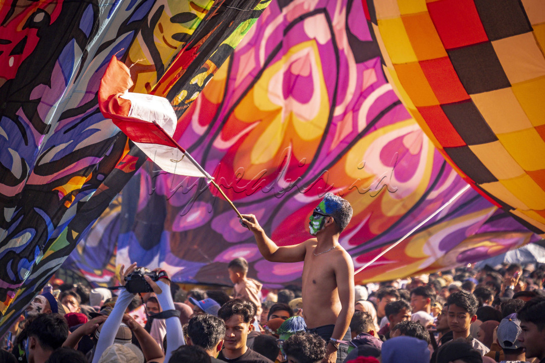 Seorang Pemuda dengan dandanan menarik dan Bendera Merah Putih merayakan keberhasilan mereka menerbangkan Balon Udara dalam festival Balon Udara Wonosobo, sebuah festival tradisi yang rutin di adakan setiap tahun di kota tersebut