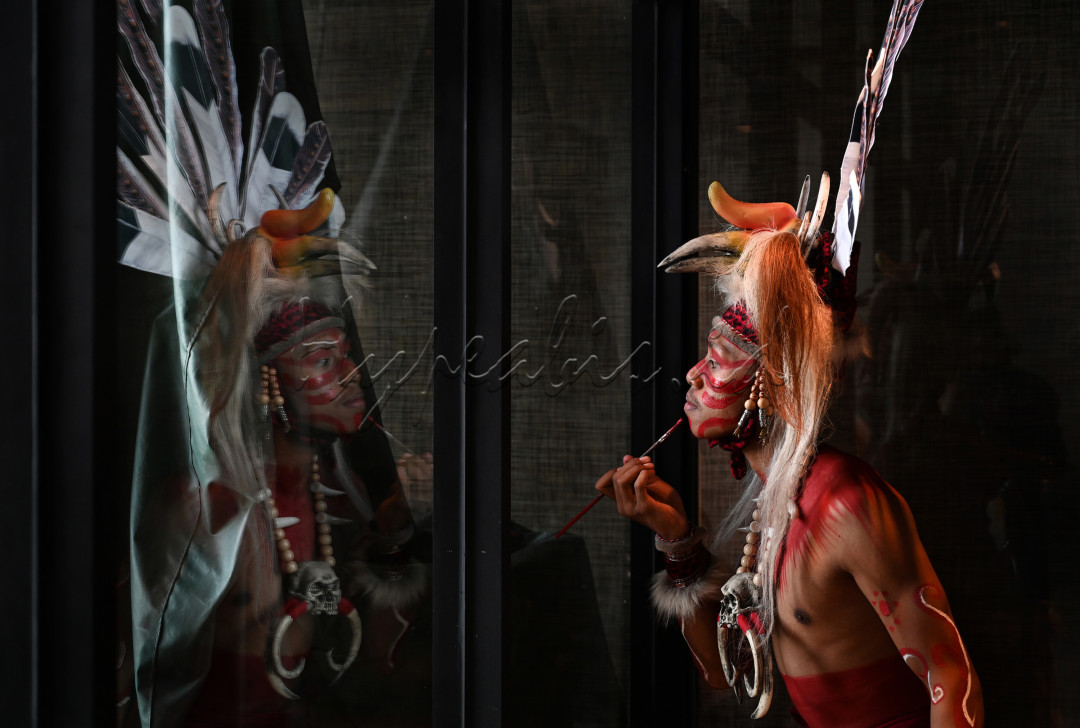 Seorang penari Dayak sedang merias dirinya dengan warna khas untuk menarikan tarian perang Mandau di acara pertunjukan di Bali.