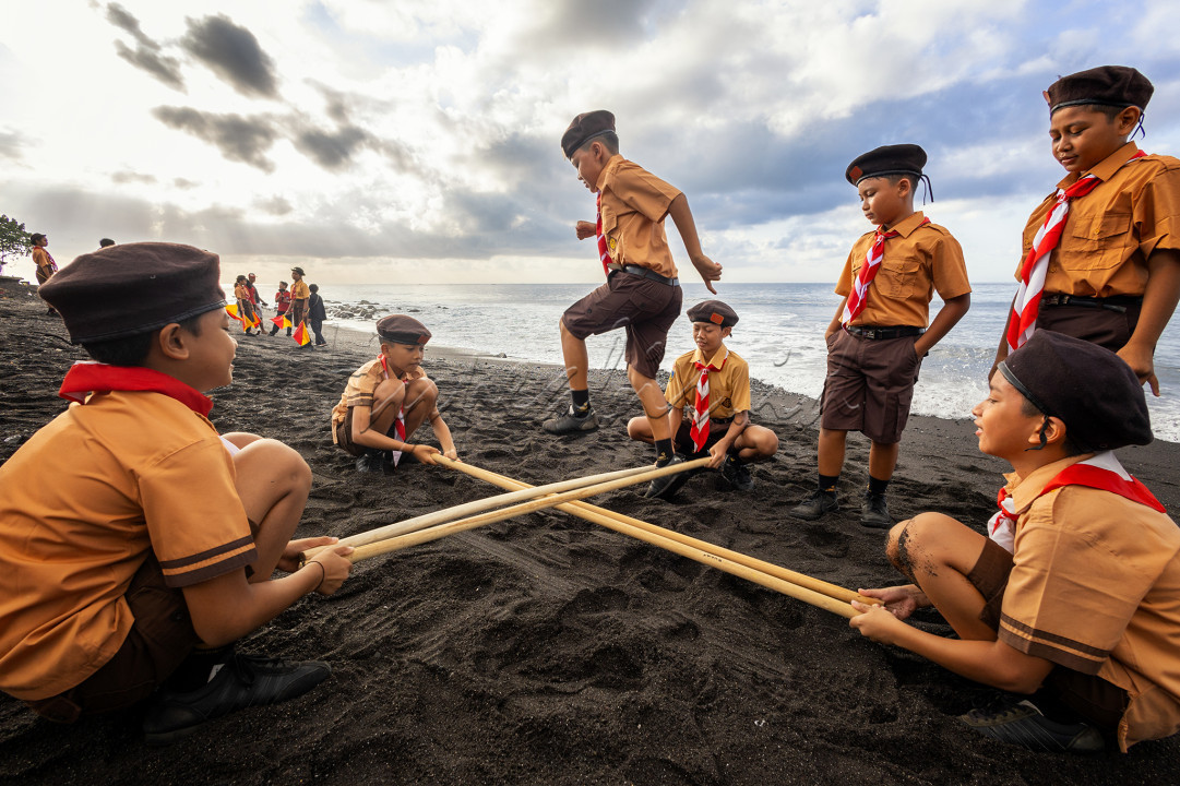Generasi Tangguh, Wajah Indonesia. Anak-anak Pramuka, Tunas Bangsa, bermain dalam keceriaan permainan tradisional di tepi pantai. Warisan budaya yang terus hidup, di tangan masa depan negeri