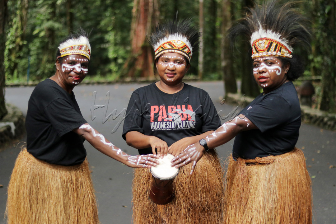 Potrait senyum mama papua dengan menggunakan pakaian adat khas kamoro dan memegang alat musik tradisional Tifa&nbsp;