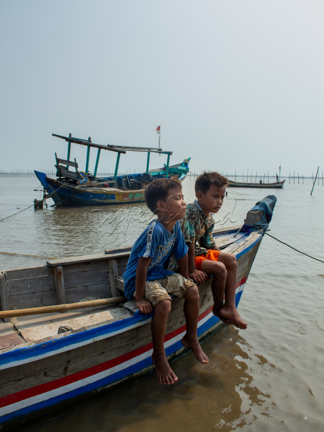 <em>wajah dua anak pribumi sedang merenung di atas sampan nelayan</em>