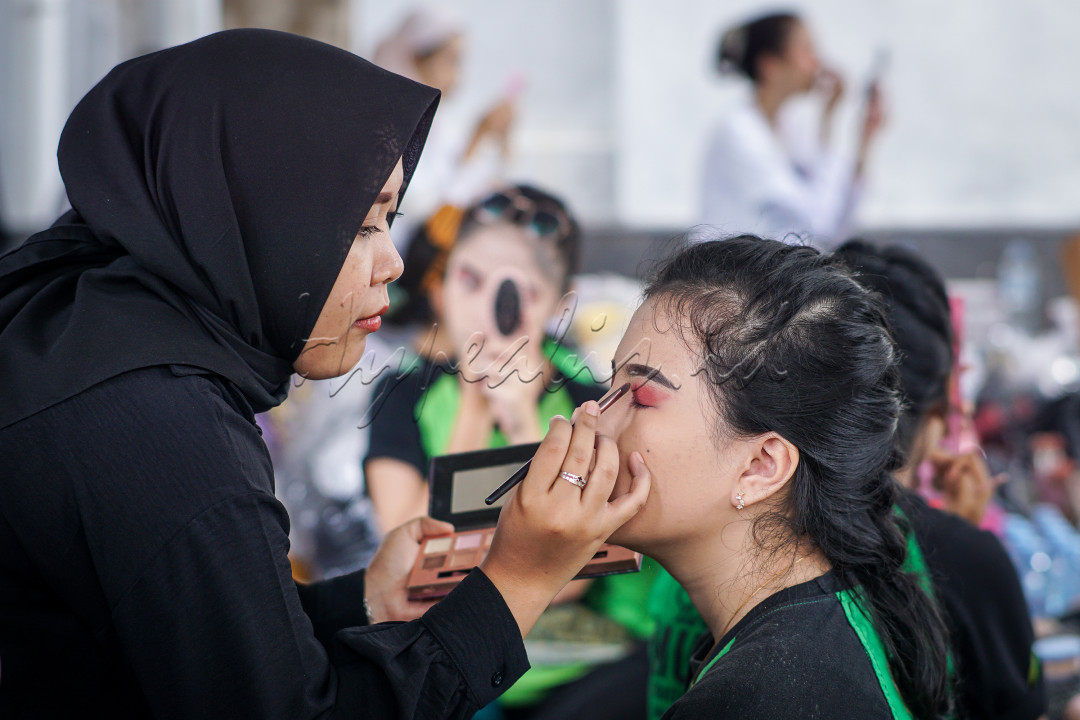 Seorang periasa wajah sedang menyelesaikan tugasnya untuk Merias Wajah seorang talent saat persiapan sebelum tampil di festival Asia Africa 2024. Asia africa festival 2024 ini memberikan wadah dan kesempatan bagi para pelaku seni kreatif untuk turut serta memeriahkan festival. Dan para talent-talent yang nantinya akan berjalan di Jalan Asia-Afrika lengkap dengan mengenakan busana budaya ini, selalu memberikan hasil terbaiknya, dengan salah satunya adalah persiapan Makeup atau Rias wajah.