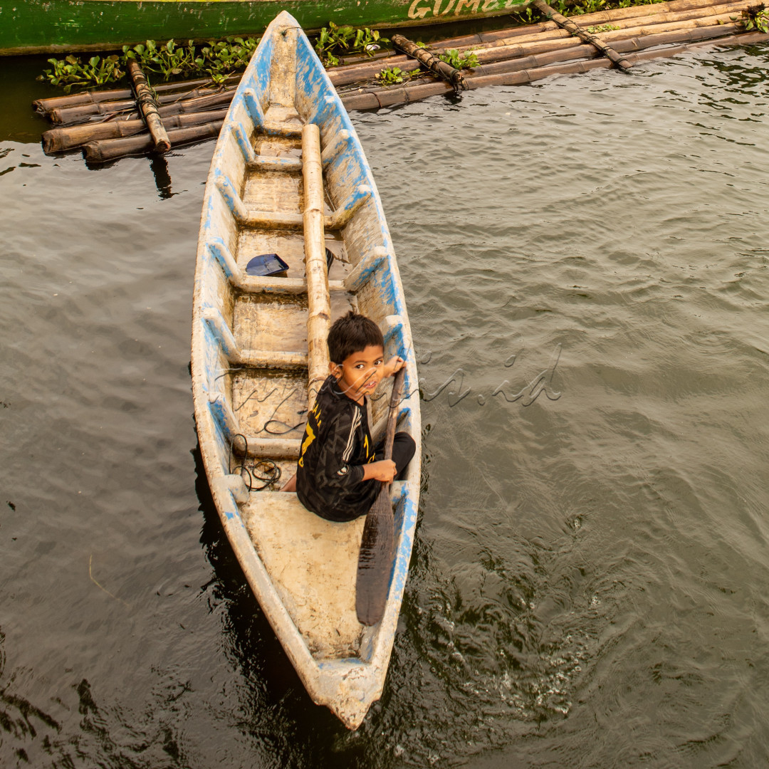 Disuatu waktu di danau terlihat anak kecil sedang bermain sambil menaiki perahu nelayan.