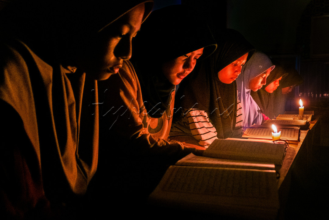 Wajah tekun dan khusuk para santri pondok pesantren ketika belajar mengaji dengan kondisi listrik padam