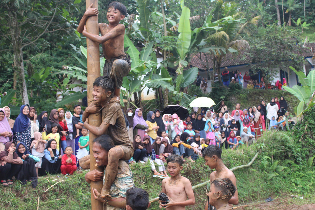 Lomba panjat pinang adalah salah satu tradisi yang paling ditunggu-tunggu dalam perayaan Hari Kemerdekaan Indonesia. Perlombaan ini melibatkan sekelompok peserta yang harus bekerja sama memanjat batang pohon pinang yang tinggi dan licin, yang telah dilumuri minyak atau oli, untuk mencapai puncak dan mendapatkan berbagai hadiah yang tergantung di atas. Lomba panjat pinang memiliki sejarah panjang yang bermula pada masa penjajahan Belanda. Awalnya, lomba ini diadakan oleh penjajah sebagai hiburan, di mana penduduk pribumi berlomba-lomba untuk memanjat batang pinang guna mendapatkan hadiah kecil. Namun, setelah Indonesia merdeka, lomba ini diadopsi dan diubah maknanya oleh rakyat Indonesia menjadi simbol perjuangan, kebersamaan, dan semangat pantang menyerah. Lomba panjat pinang lebih dari sekadar hiburan. Ini adalah simbol kerja sama dan gotong royong. Setiap peserta harus bekerja sama untuk memanjat batang yang licin, saling membantu dan mendukung satu sama lain, mirip dengan semangat kebersamaan dan perjuangan dalam sejarah bangsa Indonesia. Selain itu, lomba ini juga mengajarkan ketekunan dan pantang menyerah, mengingatkan kita akan semangat para pahlawan dalam merebut kemerdekaan. Dalam perayaan Hari Kemerdekaan, lomba panjat pinang menjadi ajang yang menggabungkan kegembiraan, tantangan, dan kebersamaan. Lomba ini mencerminkan semangat "Bhinneka Tunggal Ika" bersatu dalam keberagaman, di mana masyarakat Indonesia dari berbagai latar belakang dapat bersama-sama merayakan kemerdekaan dengan penuh suka cita.