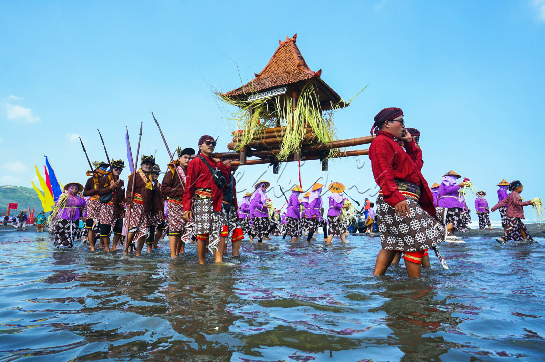 Dengan memikul jodang,para warga masyarakat desa Parangtritis,Kretek, Bantul,Yogyakarta tetap semangat melintasi aliran sungai di kawasan Pantai saat mengikuti acara Labuhan Jaladri 11/06/2024.&nbsp; Acara labuhan tersebut dilaksanakan satu tahun sekali oleh masyarakat pesisir pantai sebagai ungkapan rasa syukur kepada tuhan YME.