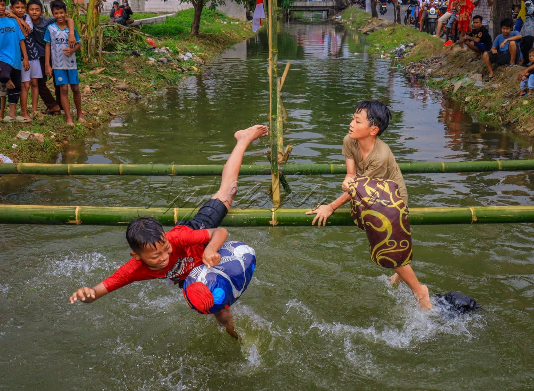 Moment lomba perang bantal anak lelaki, terlihat seorang anak yg terjatuh karena terkena pukulan bantal lawannya.