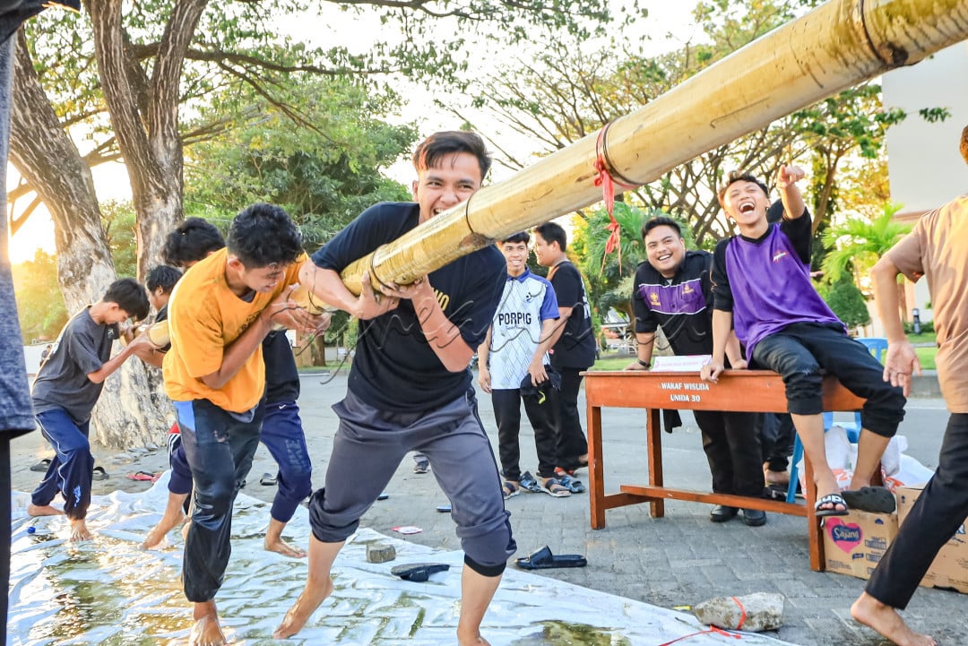 Di tengah serunya perayaan kemerdekaan, foto ini mengabadikan momen unik dari perlombaan tarik bambu permainan tradisional yang penuh semangat. Sorotan utama ada pada seorang peserta di bagian depan yang menampilkan ekspresi penuh tekad saat menarik bambu, sementara rekan-rekannya bertahan sambil merunduk, berjuang sekuat tenaga untuk memenangkan perlombaan. Di sisi lain, penonton terhibur, menunjuk peserta sambil tertawa, menikmati keceriaan di tengah perjuangan. Foto ini menggambarkan "Wajah Indonesia" dengan sempurna, perpaduan antara semangat juang, kerja keras, dan tawa riang yang selalu hadir dalam setiap kebersamaan.