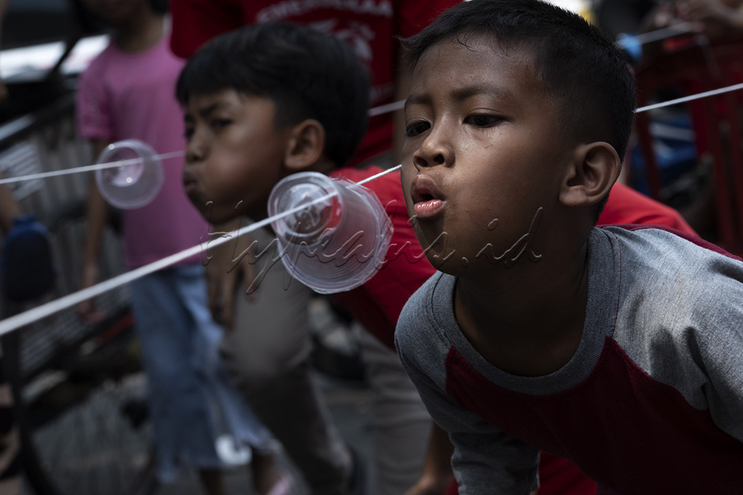 Dua orang anak sedang berlomba untuk jadi pemenang dalam lomba tiup wadah minuman air mineral dalam rangka memperingati HUT Kemerdekaan RI ke 79 di kawasan Petamburan Jakarta