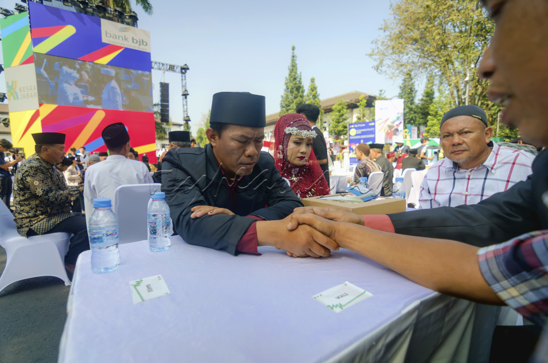 Pasangan pengantin sedang melaksanakan akad saat acara nikah massal bertempat di depan Gedung Sate, Bandung Jawa Barat. Pemerintah Provinsi Jawa Barat memberikan fasilitas Pernikahan dan Pencatatan Nikah bagi 37 pasangan dari beberapa daerah di Jawa Barat dalam rangkaian West Java Festival 2024.