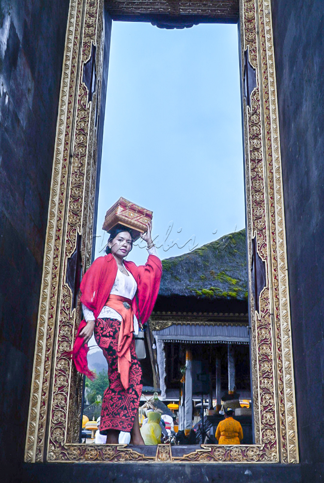Wanita Bali sedang akan melewati pintu menuju persembahyangan di Pura Besakih Bali