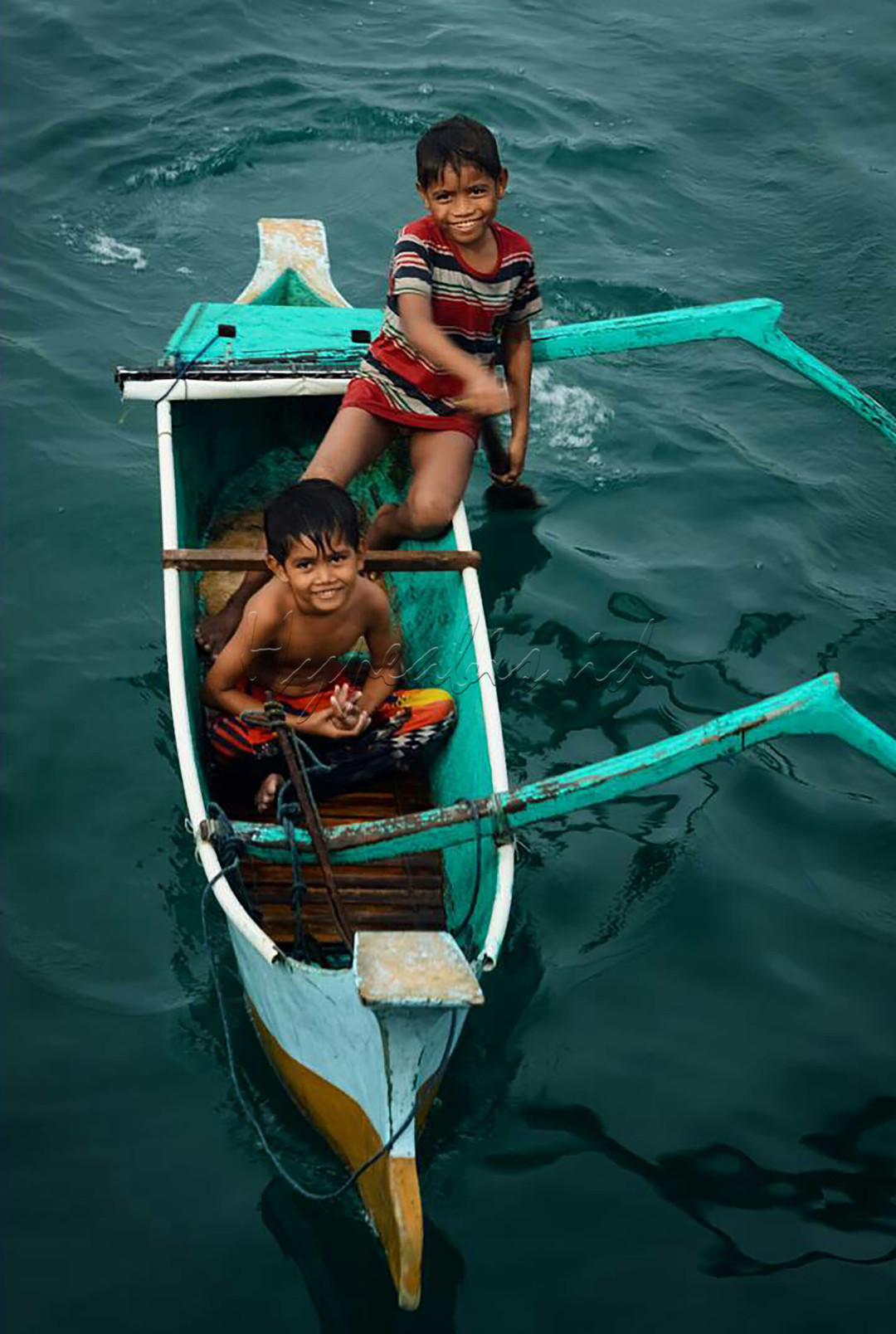 Dua anak laki-laki yang bahagia bermain di perahu mungil