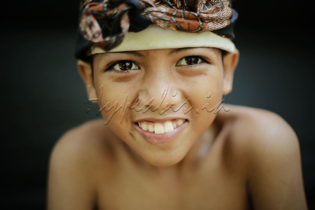 Seorang anak laki-laki yang tersenyum lebar dengan ekspresi kebahagiaan.