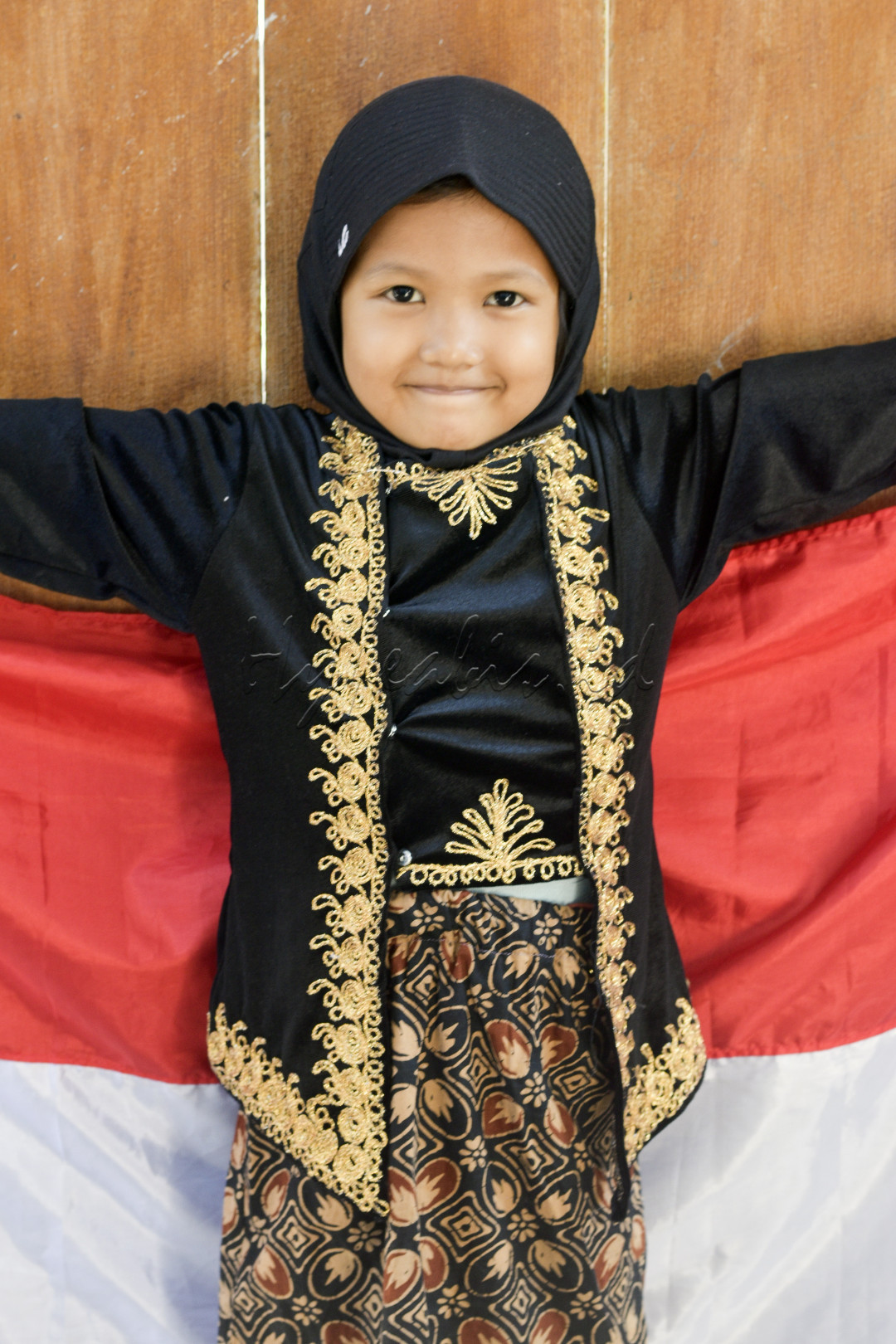 Seorang bocah gadis mengenakan pakaian adat Jawa tersenyum sambil mengepakkan bendera merah putih sebelum berangkat mengikuti kegiatan karnaval dalam rangka memperingati Hari Kemerdekaan Republik Indonesia ke-79 di Kabupaten Grobogan, Jawa Tengah, Rabu, 21 Agustus 2024.