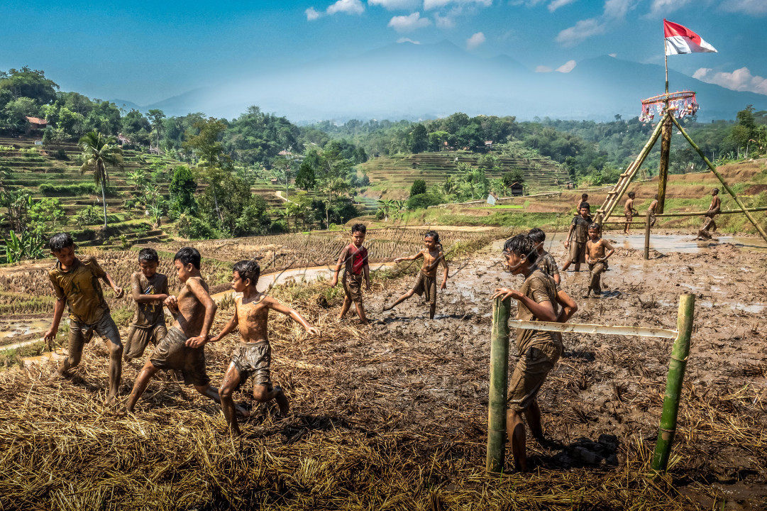 anak anak bermain bola di area sawah yang baru dipanen