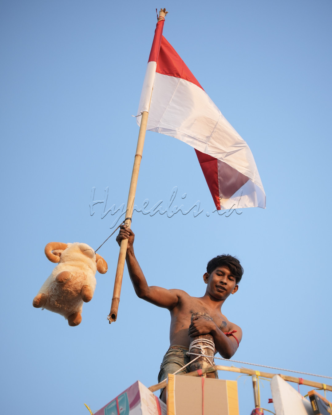 salah satu peserta panjat pinang berhasil mencapai puncak dan mengibarkan bendera merah putih