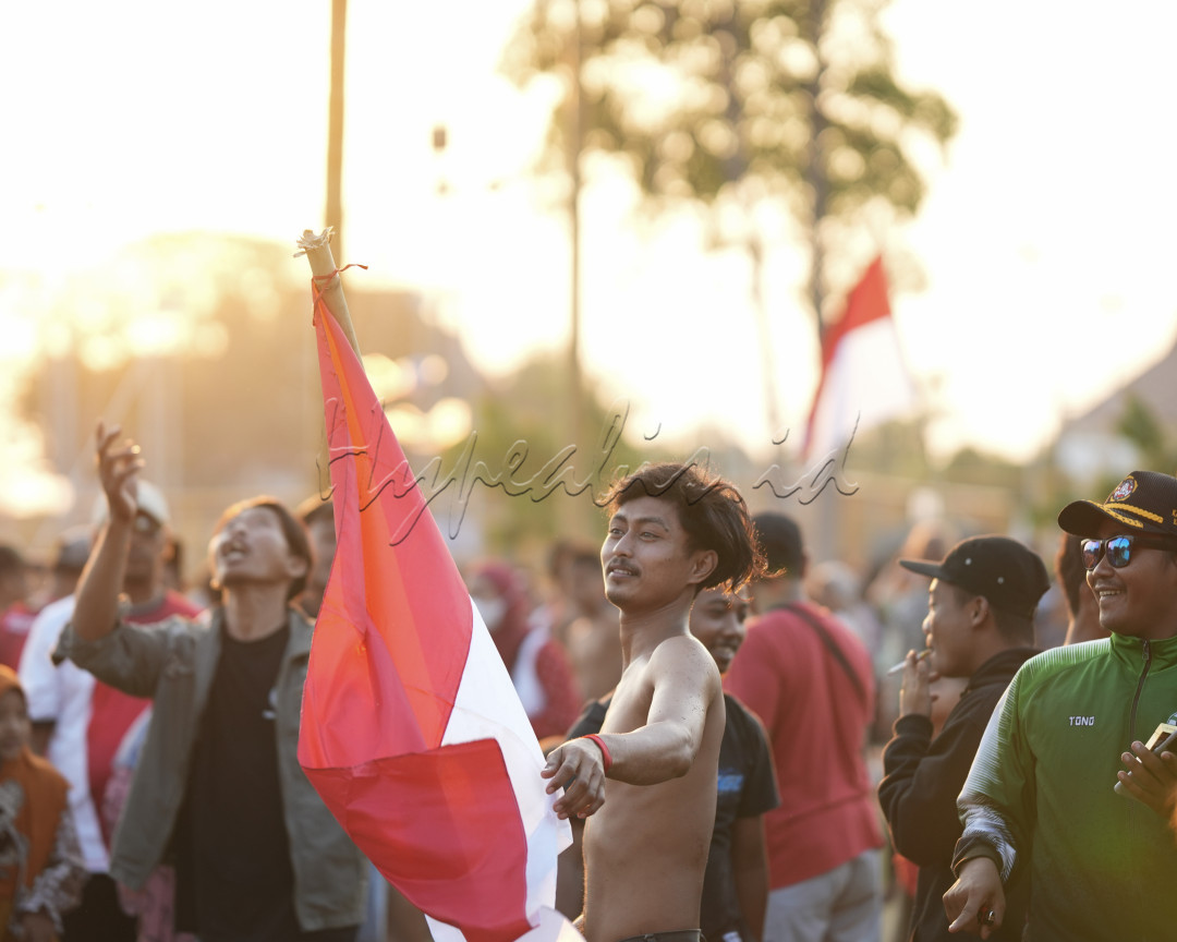 Salah satu peserta panjat pinang membawa bendera merah putih yang berhasil di dapatkan