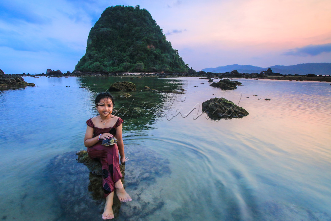 Potret gadis desa di banyuwangi yang sedang bermain di pantai Pulau Merah di sore hari dengan membawa kura kuranya