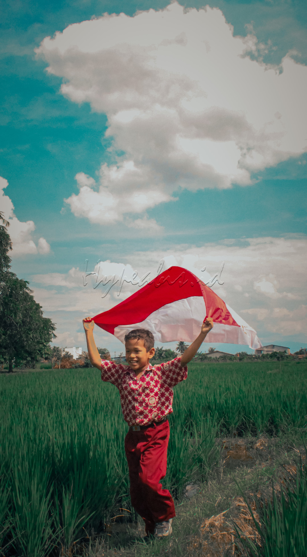 Wajah anak Generasi Muda Indonesia dengan bahagia mengibarkan bendera merah putih di atas kepala nya menggunakan pakaian sekolah kebanggaannya