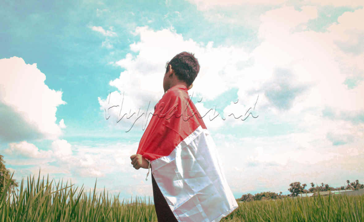 Anak Indonesia yang mencintai tanah air menyelimuti tubuhnya dengan bendera merah putih&nbsp;