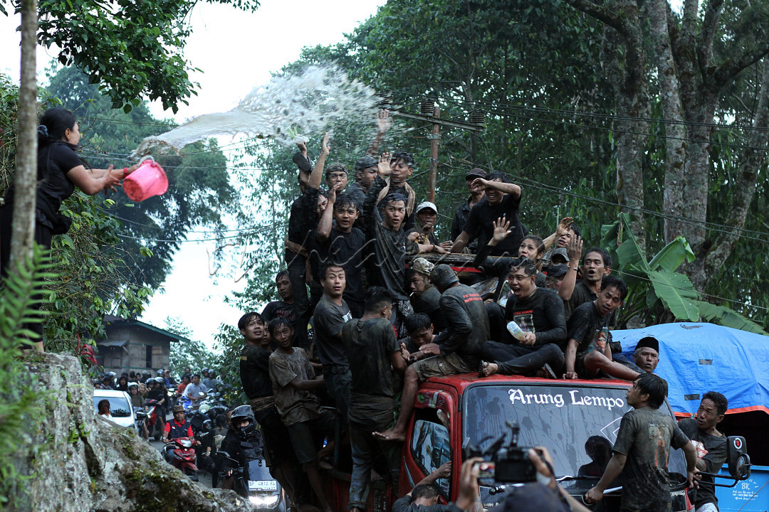Seorang perempuan menyiram kerabatnya yang sedang melintas di atas truk menuju area pemakaman di Toraja Utara, Rabu 31 Juli 2024. Prosesi kematian di Toraja diwarnai tradisi siraman kepada keluarga yang tujuannya untuk memberikan hiburan agar tidak sedih.