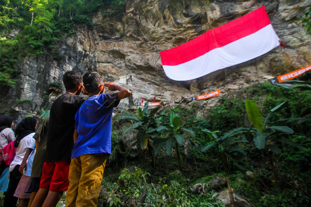 Nampak Beberapa anak yg sedang menghormati Bendera Merah Putih yang sedang di kibarakan di tebing alam Likunggavali..