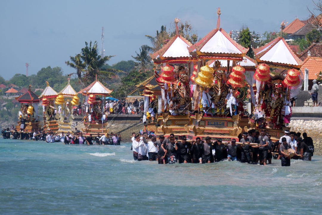Sejumlah umat Hindu mengarak tempat pembakaran jenazah saat melintasi pantai pada upacara ngaben massal di Desa Adat Karangsari, Nusa Penida, Klungkung, Bali, Kamis (18/7/2024). Upacara ngaben massal tersebut digelar setiap lima tahun sekali dengan berjalan melintasi pantai.