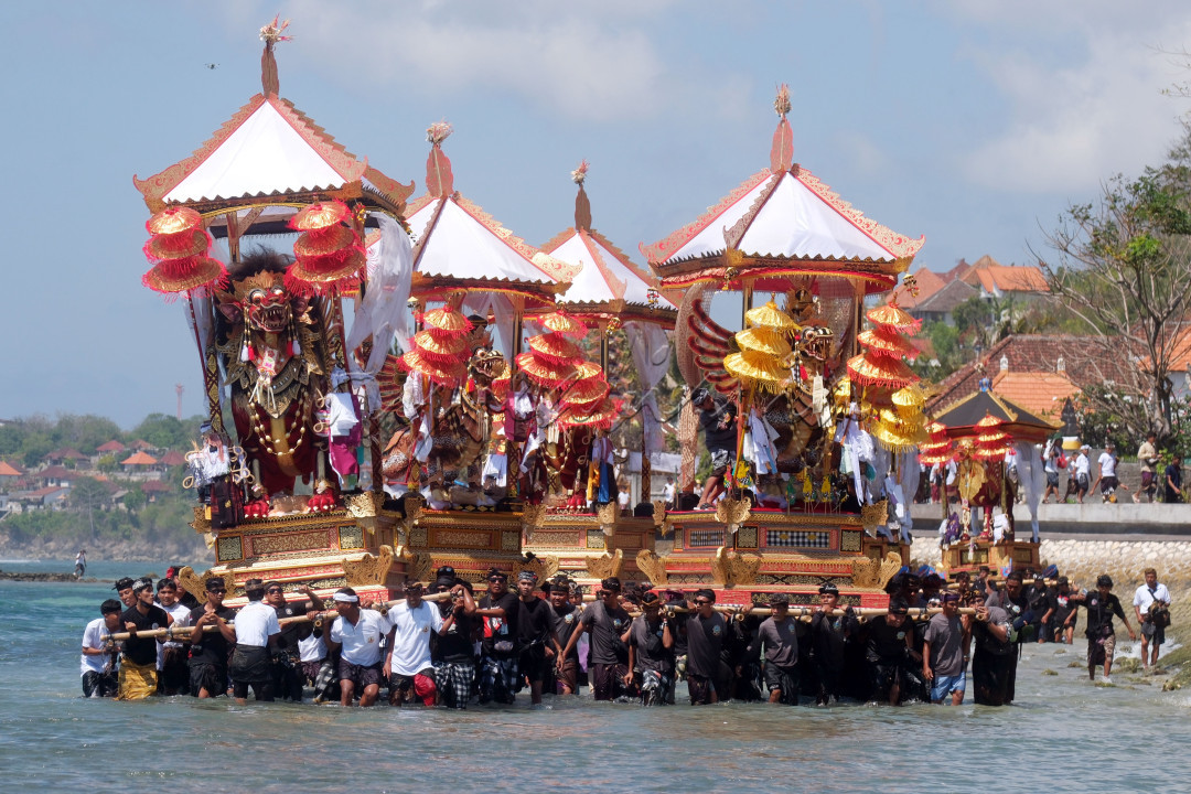 Sejumlah umat Hindu mengarak tempat pembakaran jenazah saat melintasi pantai pada upacara ngaben massal di Desa Adat Karangsari, Nusa Penida, Klungkung, Bali, Kamis (18/7/2024). Upacara ngaben massal tersebut digelar setiap lima tahun sekali dengan berjalan melintasi pantai.