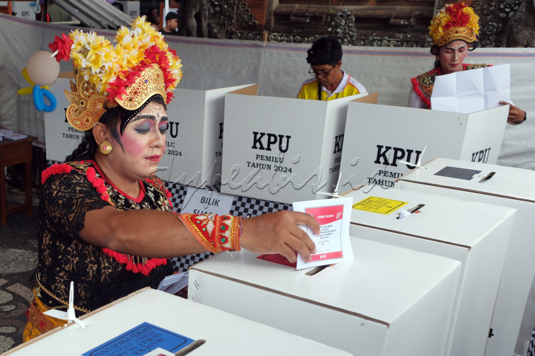 Pemilih yang juga sebagai Anggota Kelompok Penyelenggara Pemungutan Suara (KPPS) mengenakan busana kesenian Arja atau opera khas Bali saat memasukkan surat suara ke dalam kotak suara pada Pemilu 2024 di TPS 20 Banjar Blungbang, Desa Penarungan, Badung, Bali, Rabu (14/2/2024). Anggota KPPS sengaja mengenakan busana tersebut yang mengusung tema Calonarang Cupak Gerantang sebagai upaya kreatif untuk meningkatkan partisipasi pemilih pada Pemilu 2024.