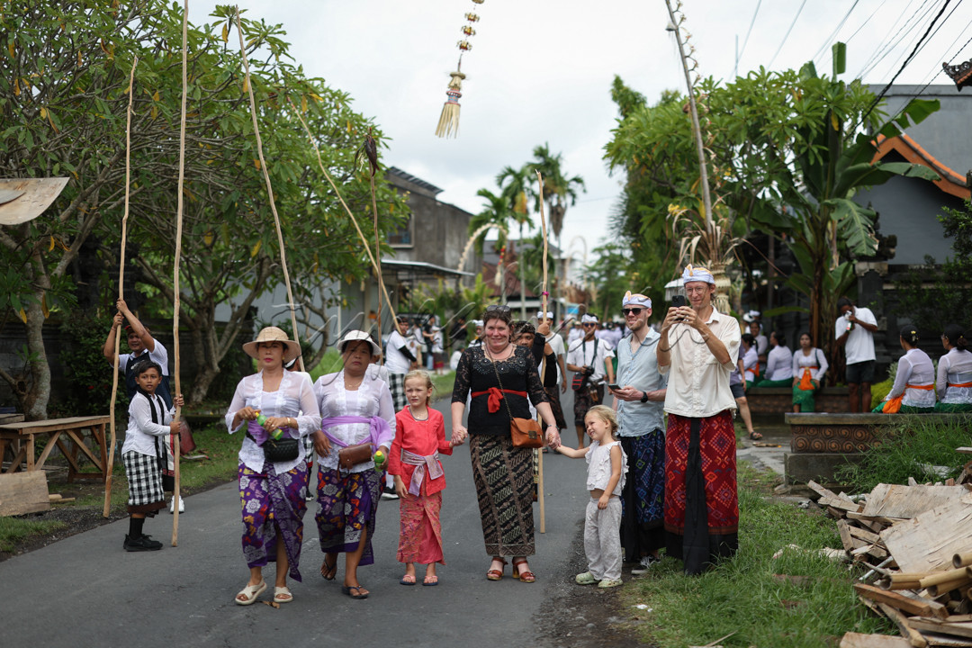 Warga Negara Asing memakai pakaian adat menyaksikan umat ??Hindu mengangkat galah saat penyelenggaraan tradisi Mekotek di Desa Adat Munggu, Bali, Indonesia, Sabtu 9 Maret 2024.